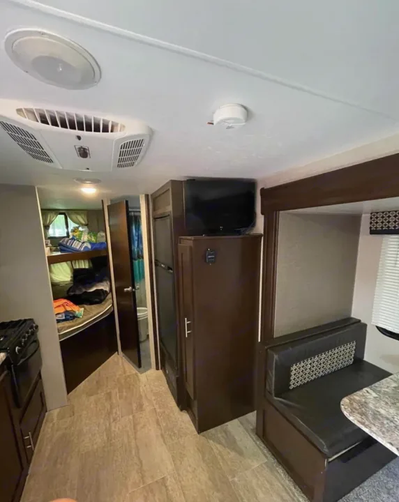 RV rental interior: living area with dinette, TV, kitchen access, and cozy bunk beds. Ideal for your next road trip.. K-Z Manufacturing Sportsmen 2019