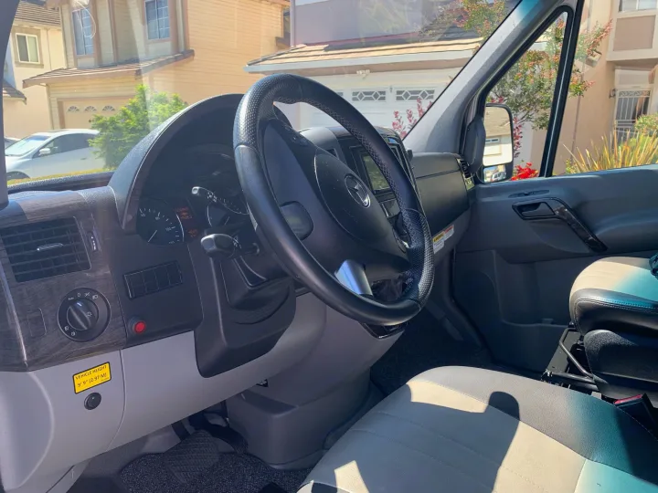 RV rental interior: driver's cockpit with dashboard, steering wheel, and visible vehicle height warning.. Roadtrek Agile Ss 2019