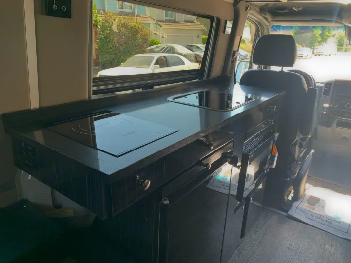Step into this RV rental's sleek kitchen! Features include an induction cooktop, sink, and built-in microwave in a camper van.. Roadtrek Agile Ss 2019