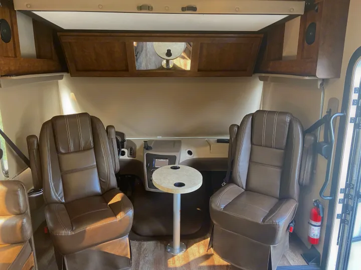 RV rental: Comfortable and spacious RV cockpit with brown leather seats, a table, and overhead storage. Ready for travel!. Forest River Fr3 2017