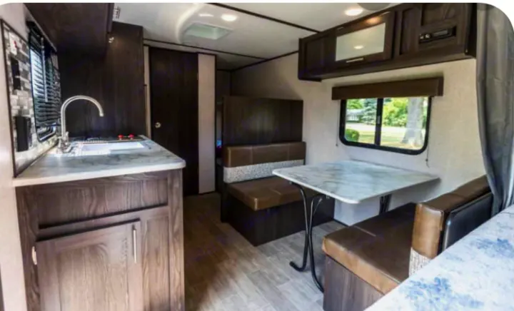 Inside this modern RV rental, see the kitchen with sink, cozy dinette seating, and overhead cabinets. Ideal camper interior.. Coleman COLEMAN LANTERN 2021