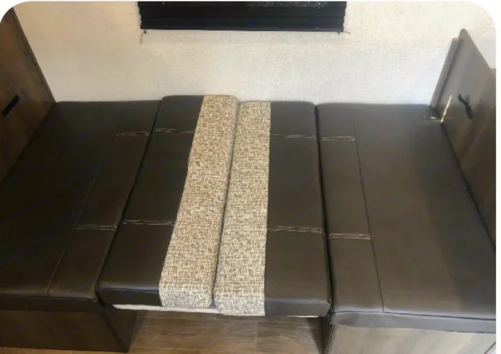 RV rental dinette with brown cushions and patterned inserts, converts to a bed. Ideal compact sleeping/seating area.. Coleman COLEMAN LANTERN 2021