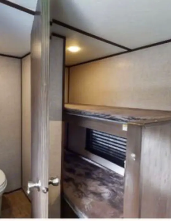 RV rental interior featuring compact bunk beds with a window, and a glimpse of the bathroom area through an open door.. Coleman COLEMAN LANTERN 2021