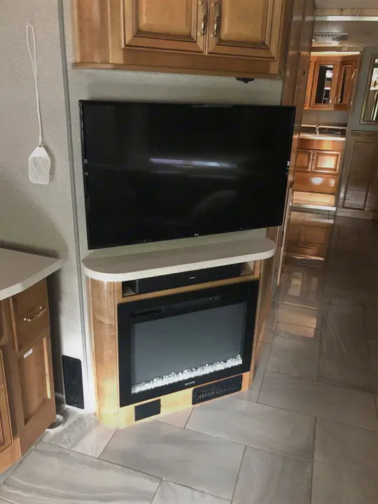 RV rental: Modern entertainment center with LG TV, Bose soundbar, and electric fireplace. Light wood cabinetry & tile floor.. Fleetwood Discovery 2019