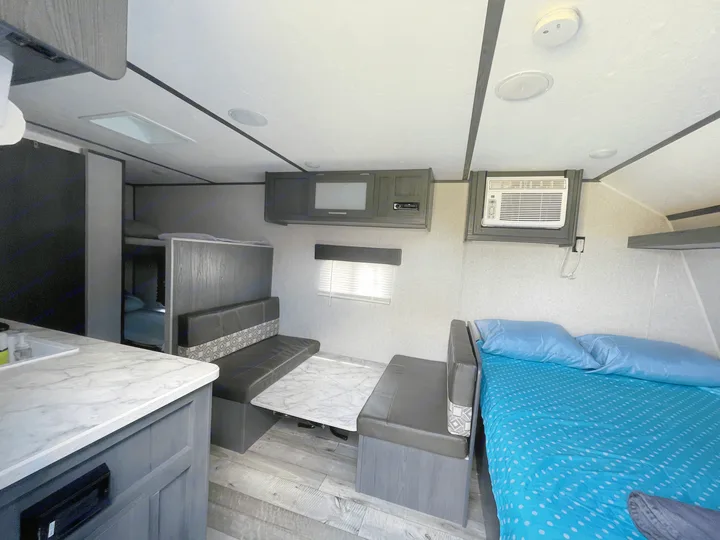 Step inside this rv rental, revealing a well-appointed interior with a kitchen, dinette, comfortable bed, and bunk beds.. Dutchmen Aspen Trail 2021