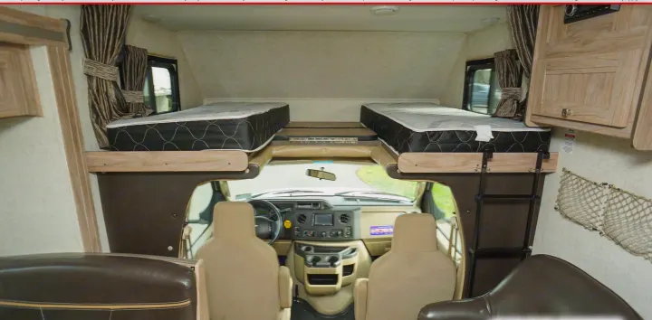 RV rental interior: Cab-over sleeping area with two mattresses, driver's cockpit, and side storage nets.. Forest River Sunseeker 2019