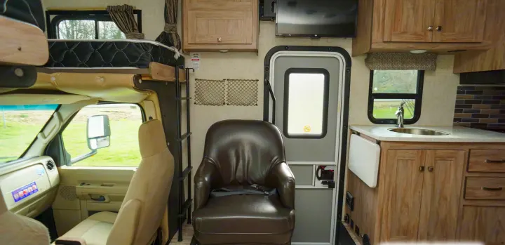 Inside a comfortable RV rental: cockpit, overhead bunk, ladder, lounge chair, kitchen with sink & cabinets, TV.. Forest River Sunseeker 2019