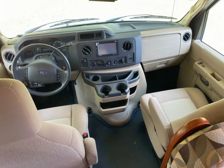 Spacious Ford E-Series RV rental interior. Cockpit view with steering wheel, dash, infotainment, and front seats ready for travel.. Forest River Ford Sunseeker 2013