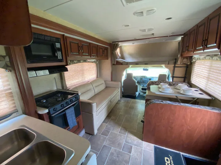 This RV rental interior features a kitchen (sink, stove, microwave), sofa, dinette, and overhead bunk. Ready for adventure!. Forest River Ford Sunseeker 2013