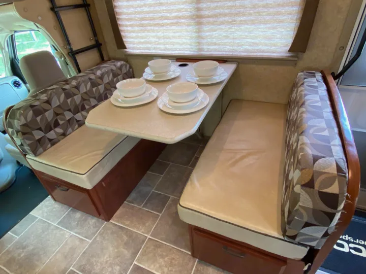 This RV rental dinette features a table set for four, with comfy patterned seating, ideal for your next motorhome trip.. Forest River Ford Sunseeker 2013