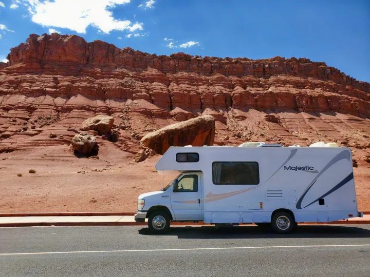 RV rental parked by towering red rock cliffs, showcasing a scenic desert road trip.. Thor Motor Coach Four Winds Majestic 2009