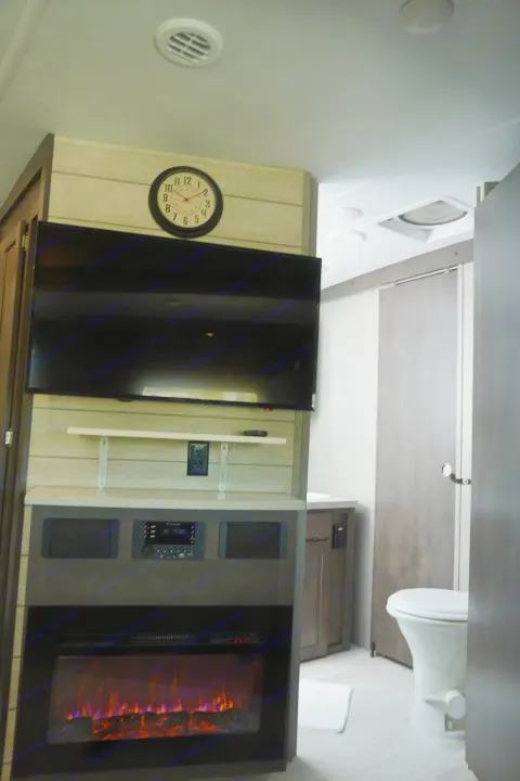 Modern RV rental interior features: a large TV, electric fireplace, and accessible bathroom with toilet. Enjoy comfortable travels.. Forest River Flagstaff Super Lite 2021