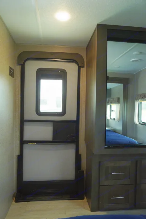 RV rental interior featuring a screen entry door, overhead lighting, and a mirrored partition revealing the compact bedroom.. Forest River Flagstaff Super Lite 2021