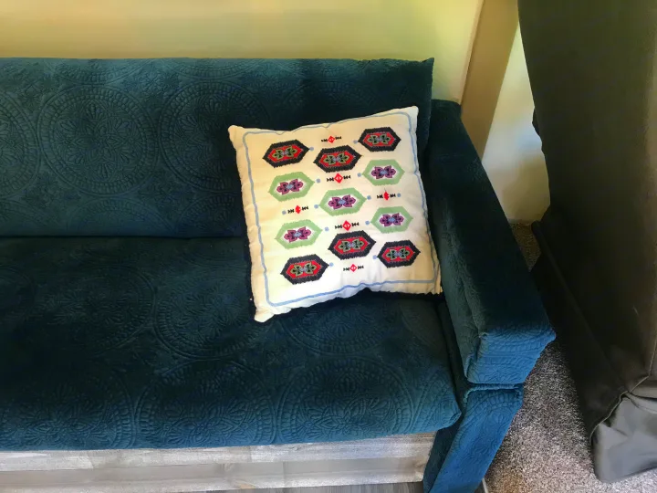 Comfortable dark blue quilted couch and patterned pillow in an RV rental interior, perfect for relaxing travel.. Thor Vegas 2016