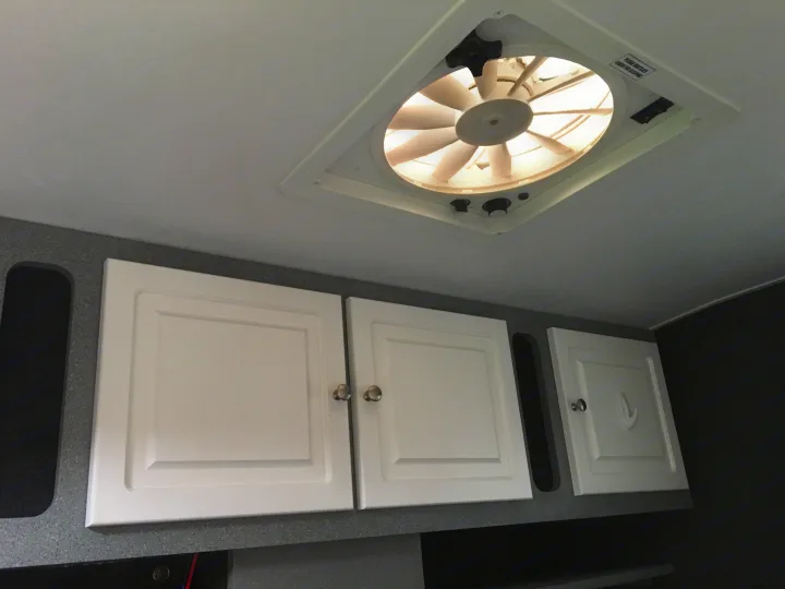 RV rental interior showing a ceiling vent fan for ventilation and white overhead storage cabinets.. Little Guy Other 2011