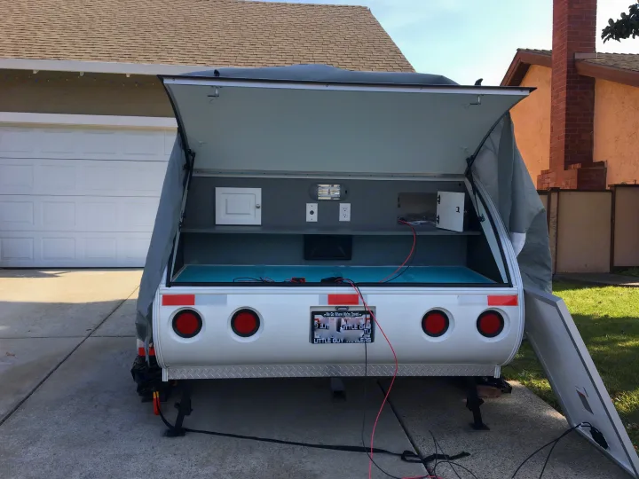 Rear view of an open small **rv rental** trailer. Interior storage, power outlets, & solar panel connections visible.. Little Guy Other 2011