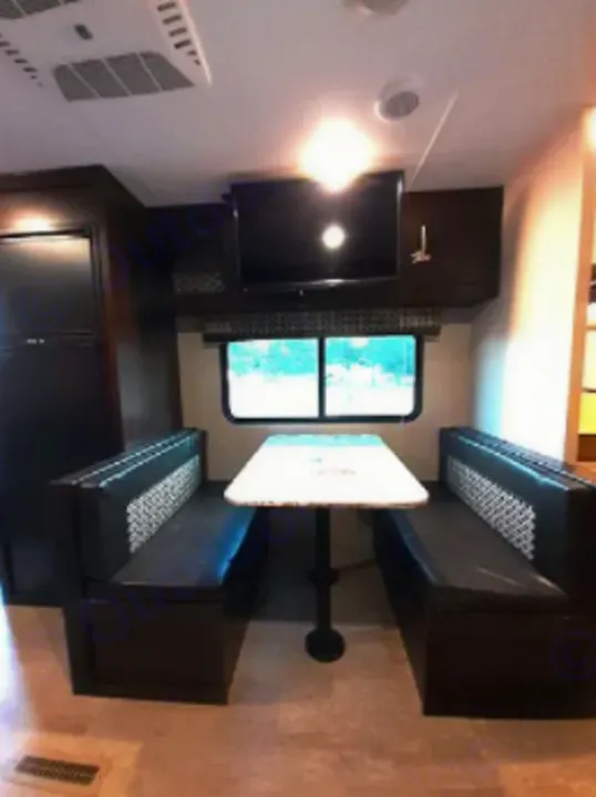 RV rental interior shows a dinette with patterned benches, table, TV, and fridge, offering a cozy travel space.. KZSP Sportsman 260 2019
