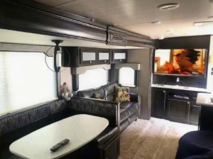 Spacious RV rental interior with dining booth, sofa, and TV entertainment center. Enjoy a cozy living space.. North Trail Ultralight 2019