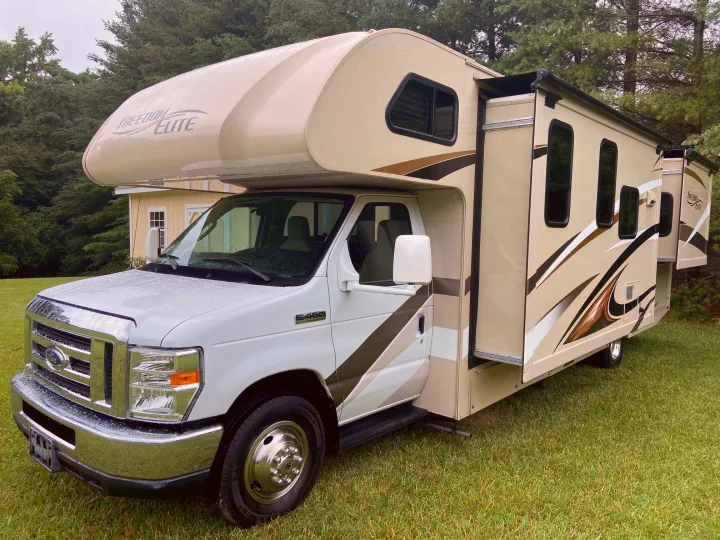 Explore with this Freedom Elite Class C motorhome, perfect for an rv rental. Parked outdoors with extended slide-out.. Thor Motor Coach Freedom Elite 2017