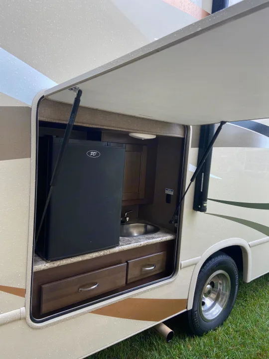 This RV rental offers an outdoor kitchen with a fridge and sink, great for convenient camping amenities.. Thor Motor Coach Freedom Elite 2017