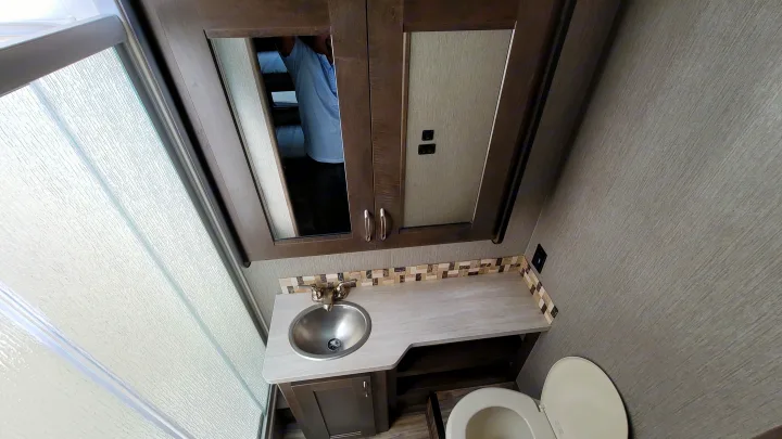 Clean RV rental bathroom showing vanity, sink, mirror, toilet, and textured shower glass.. Nexus Wraith 2022