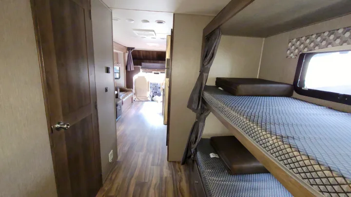 Experience RV rental comfort: spacious interior with bunk beds, a cozy hallway, and view into the living and driver's areas.. Nexus Wraith 2022