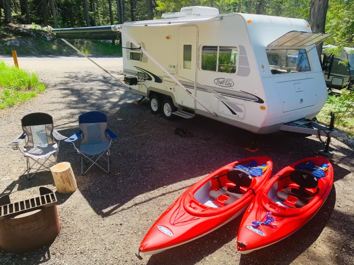 Enjoying an RV rental adventure: a camper with awning, two kayaks, chairs, and fire pit at a scenic wooded campsite.. Travel Lite Travel-Lite 800 2003