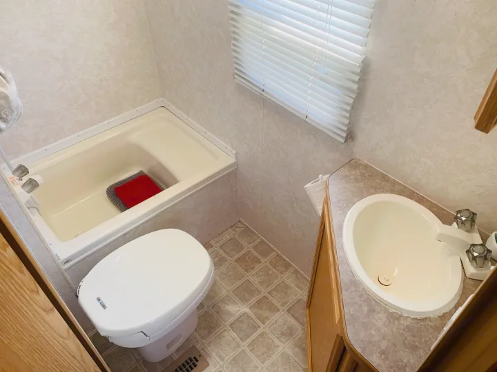 Compact RV rental bathroom with tub, toilet, and sink. Clean and functional space.. Travel Lite Travel-Lite 800 2003