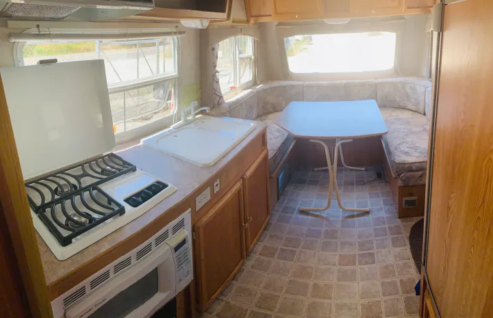 RV rental interior: kitchen with a stove, sink, microwave, and a cozy U-shaped dinette area for meals.. Travel Lite Travel-Lite 800 2003