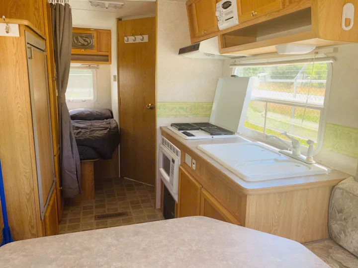 Bright RV rental interior: full kitchen, comfy bed area, and dining space. Ready for your road trip!. Travel Lite Travel-Lite 800 2003