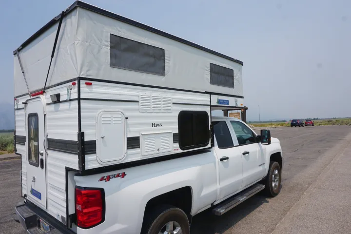 White 4x4 pickup with a pop-top Four Wheel Campers Hawk truck camper, perfect for an RV rental.. Chevrolet Silverado 2020
