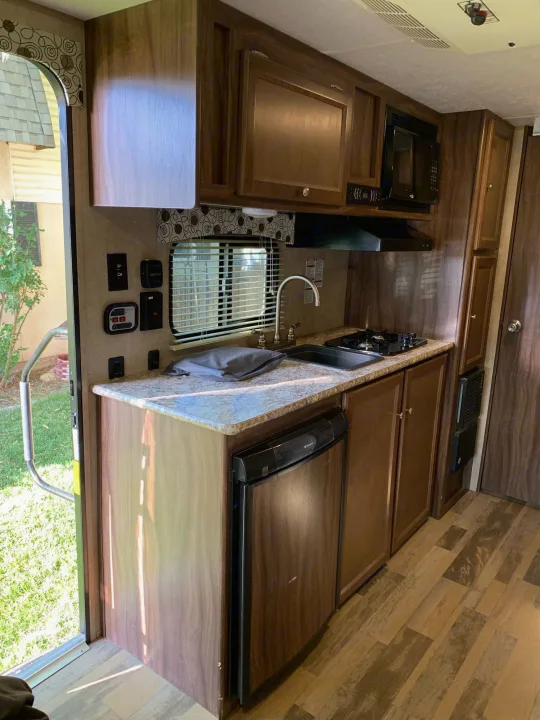 This RV rental kitchen features a sink, stove, microwave, fridge, and ample counter space, ideal for travel.. Coachmen Clipper 2017