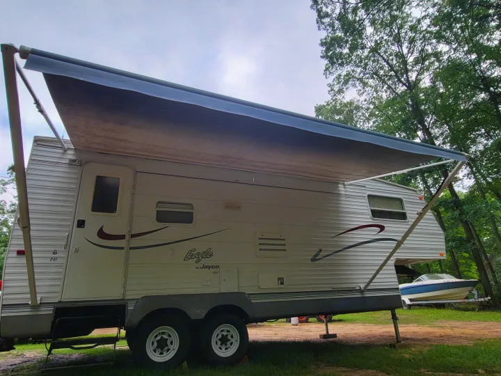 This Eagle by Jayco RV rental, with its extended awning, is set up for outdoor camping near a boat.. Jayco Eagle 2002