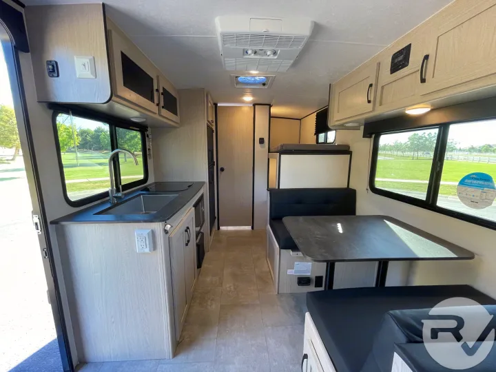 Spacious RV rental interior featuring a kitchen, dinette with bunk, light cabinetry, and ample storage. Perfect camper for travel.. Coachmen Apex 2021
