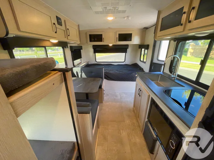 Spacious RV rental interior with kitchen, dinette, bunk beds, and rear bed for comfortable travel.. Coachmen Apex 2021