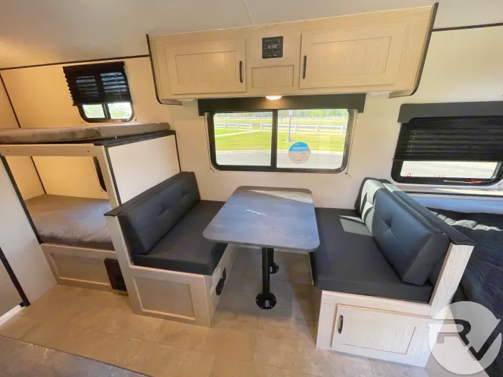 RV rental interior featuring a cozy dinette with table and bunk beds, perfect for travel.. Coachmen Apex 2021