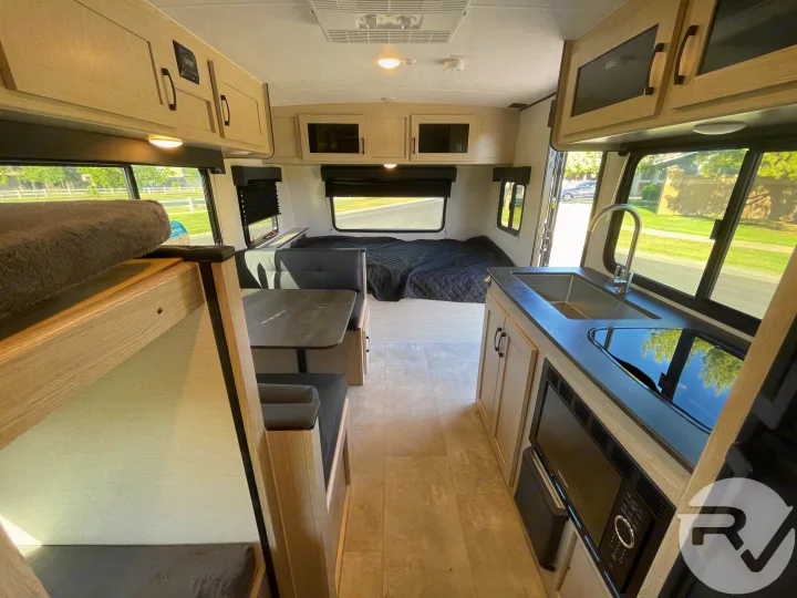 This spacious RV rental interior features a kitchen, dinette, rear bed, and bunk. Enjoy comfortable living on your next adventure.. Coachmen Apex 2021