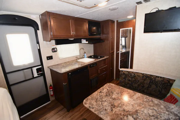 RV rental interior showcasing a compact kitchen, dinette, and TV. Perfect for road trips and comfortable camping adventures.. Keystone RV Hideout 2017