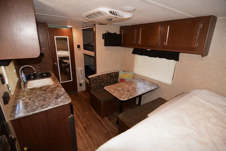 RV rental interior view: compact kitchen, dinette, bunk beds, and main sleeping area equipped for travel.. Keystone RV Hideout 2017