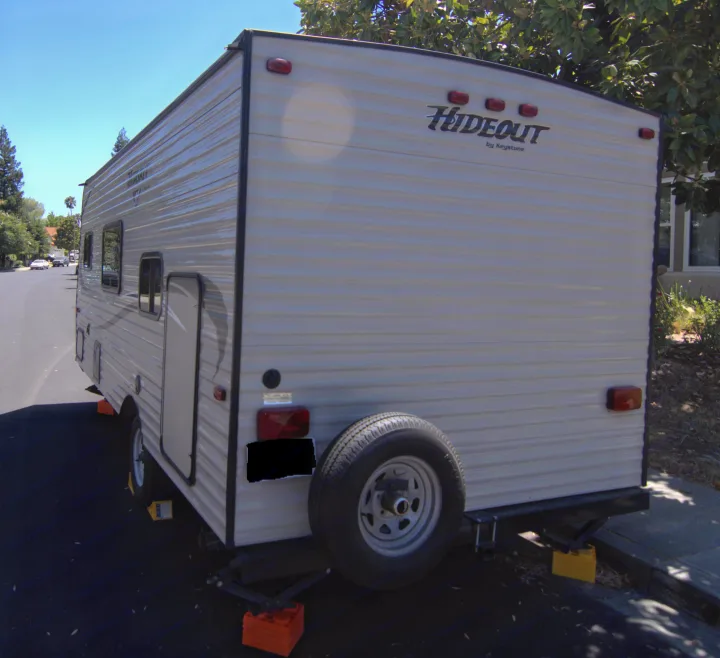 Rear and side view of a light-colored Hideout by Keystone travel trailer, ideal for an RV rental.. Keystone RV Hideout 2017