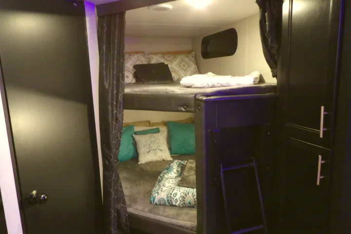Comfortable bunk beds in this RV rental's interior, featuring privacy curtains, pillows, and storage.. Forest River Cherokee Grey Wolf 2021