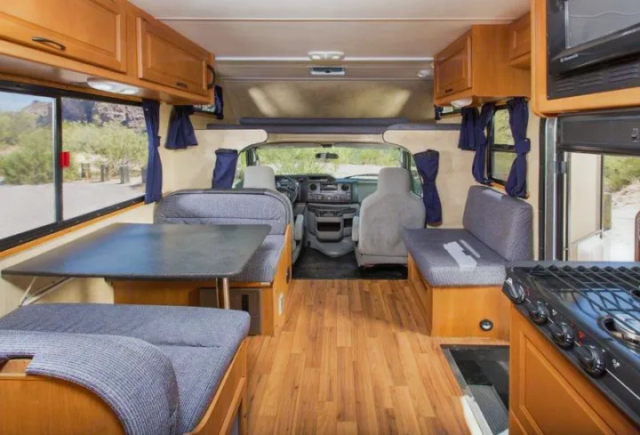 Spacious RV rental interior with wood floors, dining booth, kitchen, and driver's cab, ready for adventures.. Thor Motor Coach Four Winds Majestic 2013