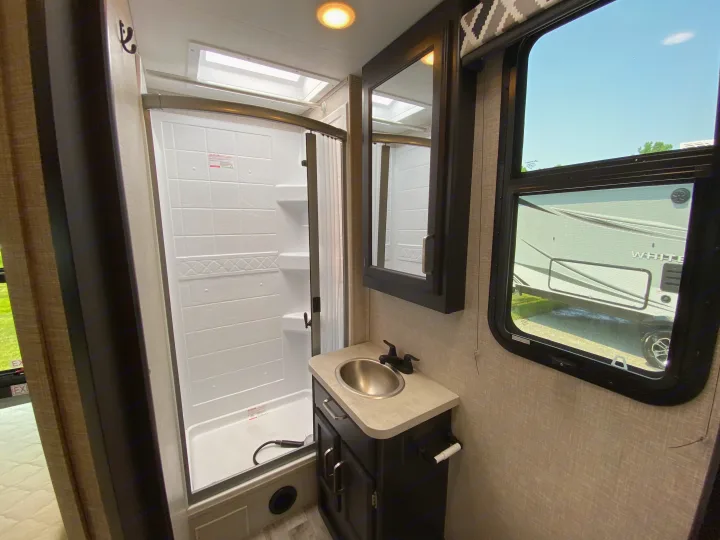 RV rental bathroom features: compact shower, sink, and mirror. Ready for comfortable travel.. Jayco Redhawk 2025