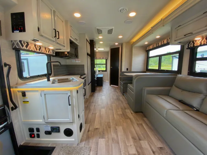 Explore this modern RV rental interior! Features a full kitchen, comfy dining/lounge area, and wood-look floors. Your mobile home on wheels.. Jayco Redhawk 2025