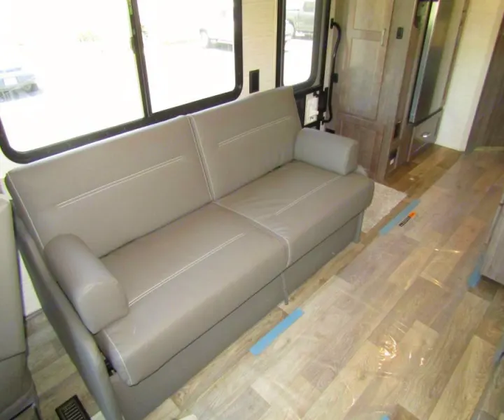 RV rental living area featuring a modern gray sofa, large windows, and durable wood-look flooring.. Winnebago Vista 2022