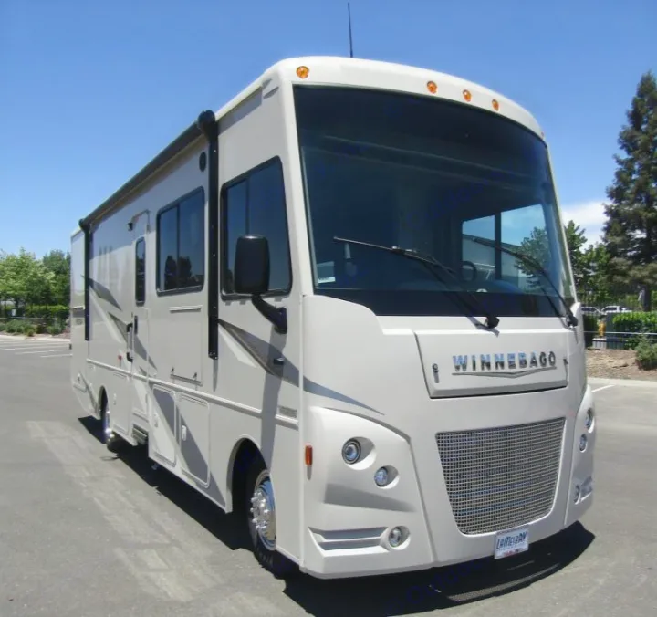 Light-colored Winnebago Class A RV for rent, featuring an awning and large front windshield.. Winnebago Vista 2022