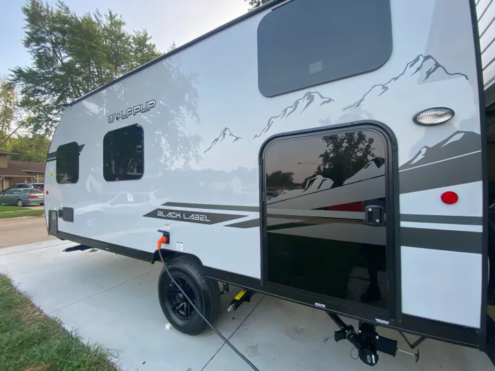 Side view of a light gray Wolf Pup travel trailer, with mountain decals, ready for an rv rental adventure.. Forest River Other 2021