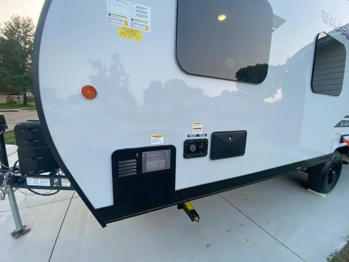White RV rental's front side, featuring utility hookups, an orange marker light, and tinted windows.. Forest River Other 2021