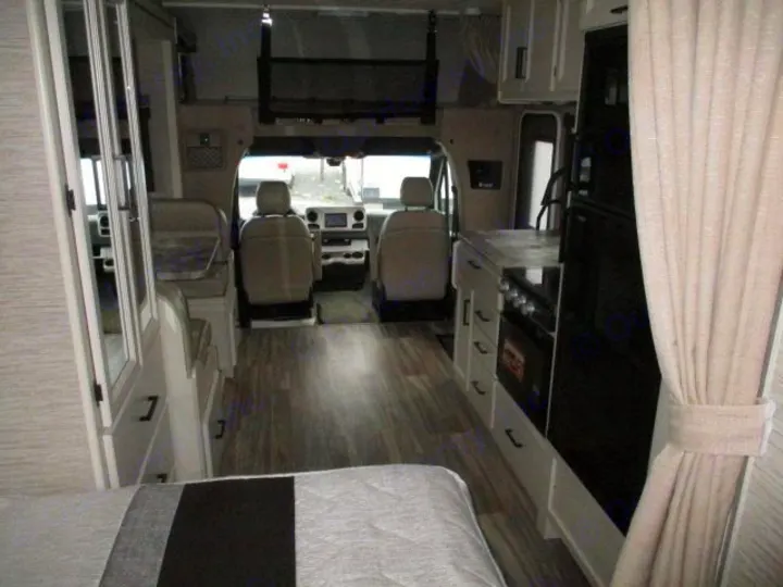 Explore this RV rental's inviting interior, showcasing a full kitchen, driver's cabin, and cozy sleeping area with modern finishes.. Thor Motor Coach Four Winds Sprinter 2021