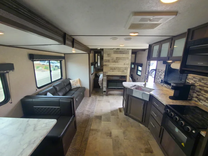 Spacious modern RV rental interior with full kitchen, living room sofa, and marble dining table.. Dutchmen Coleman 2020